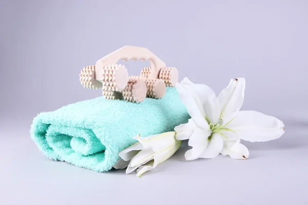 Wooden roller brush, towels and lily on grey background — Stock Photo, Image