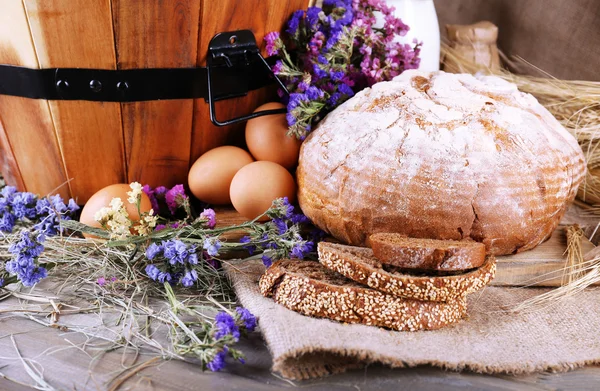 Gran canasta redonda de madera con verduras, leche y pan sobre fondo de saco — Foto de Stock