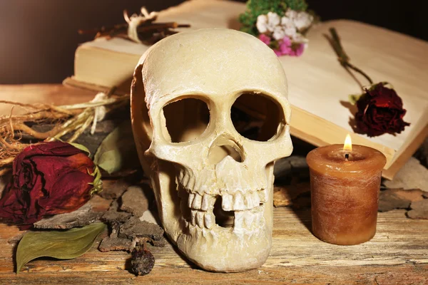 Crânio humano com pétalas de rosa secas e vela na mesa de madeira, close-up — Fotografia de Stock