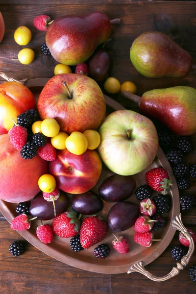 Different berries and fruits on tray on wooden table close-up — Stock Photo, Image