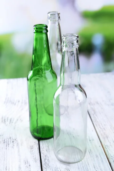 Botellas de vidrio vacías en la mesa sobre fondo brillante — Foto de Stock