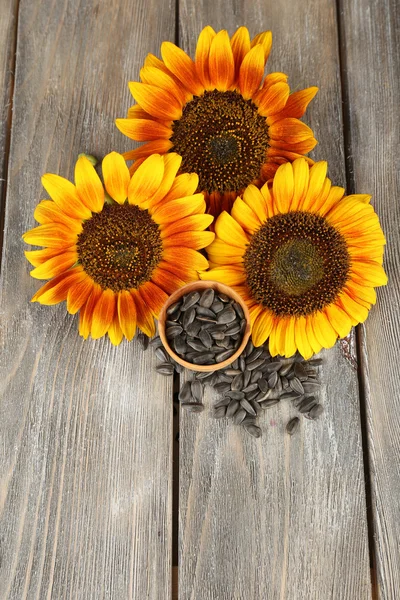 Sonnenblumen und Samen in Schale auf Holzgrund — Stockfoto