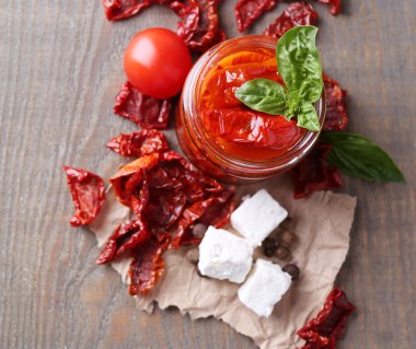 Cam Kavanoz, fesleğen yaprakları ve beyaz peynir renk ahşap zemin üzerinde güneş kurutulmuş domates