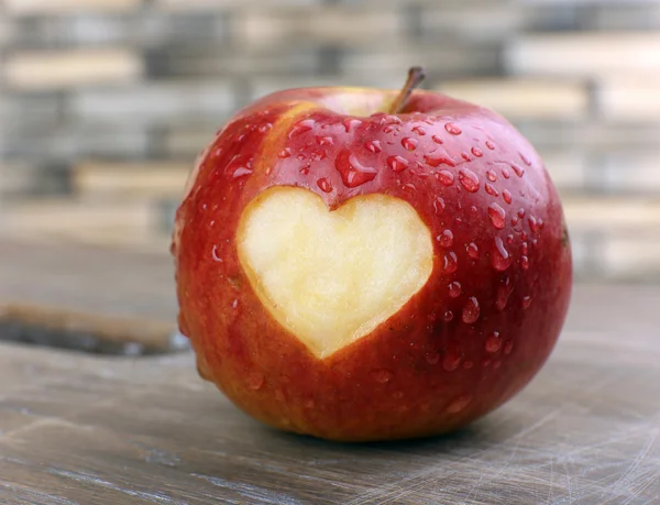 Pomme rouge avec coeur sur table en bois, gros plan — Photo