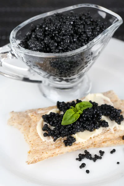 Rebanada de pan con mantequilla y bote con caviar en el plato de primer plano —  Fotos de Stock