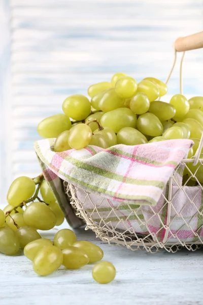 成熟的葡萄在金属篮子里用餐巾在浅色背景上木制的桌子上 — 图库照片