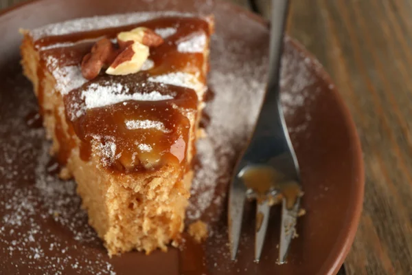 Pièce de gâteau délicieux à moitié mangé sur une table en bois — Photo