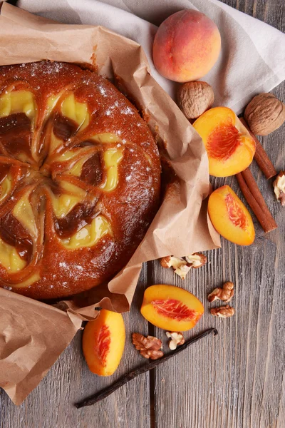 Delicious cake with peach and nuts on wooden table close up — Stock Photo, Image