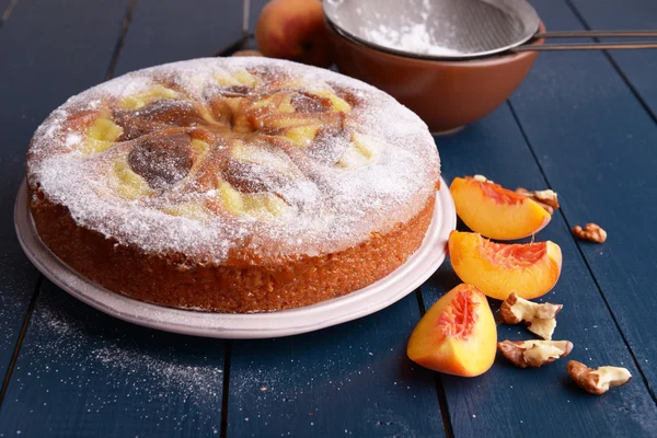 Delicious cake with peach and nuts on wooden table — Stock Photo, Image