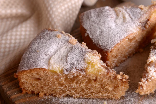 Pieces of delicious cake on cutting board on wooden table — Stock Photo, Image