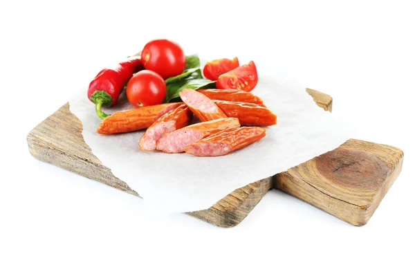 Smoked thin sausages and vegetables on cutting board, isolated on white — Stock Photo, Image