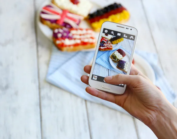 Tangan membuat foto sandwich dengan bendera di ponsel untuk jejaring sosial — Stok Foto