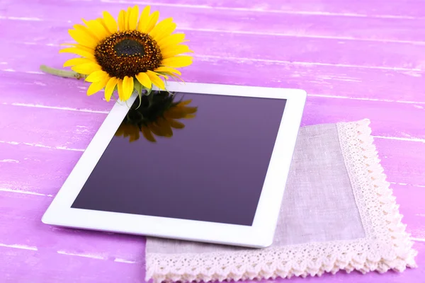 Tablet e girassol em guardanapo em fundo de madeira — Fotografia de Stock