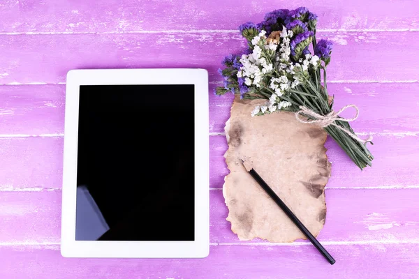 Tablet, bunch of flowers and piece of paper and pencil on wooden background — Stock Photo, Image