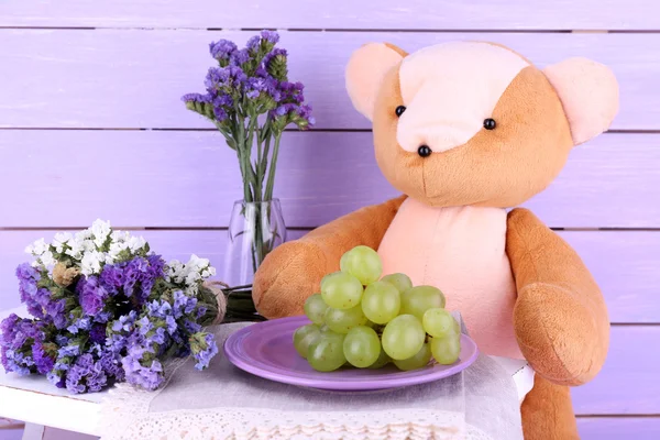 Toy bear and grapes on plate — Stock Photo, Image