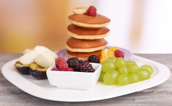 Pfannkuchen mit Früchten und Beeren auf Teller auf Tisch auf hellem Hintergrund — Stockfoto