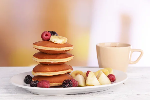 Panqueque con frutas y bayas en el plato en la mesa sobre fondo brillante — Foto de Stock