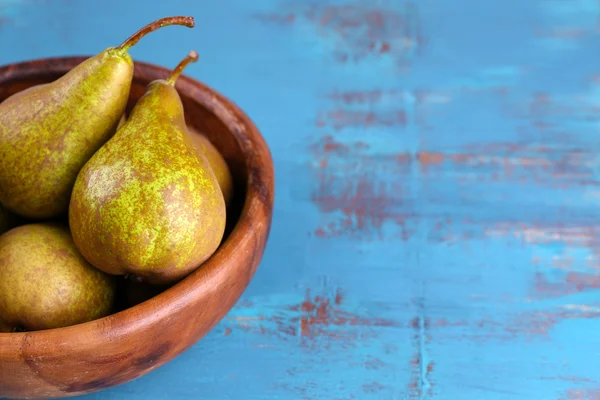 Rijpe peren in kom, op een houten achtergrond kleur — Stockfoto