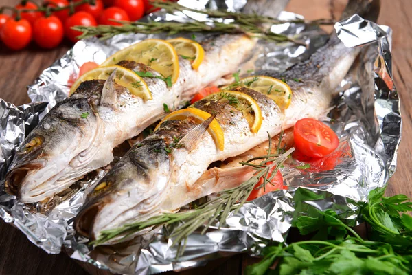 Sabroso pescado al horno en papel de aluminio en primer plano de la mesa — Foto de Stock