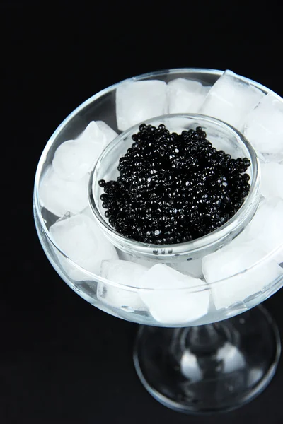 Ciotola di vetro di caviale nero e ghiaccio in calice su sfondo scuro — Foto Stock