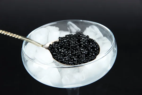 Black caviar in metal spoon and ice in goblet — Stock Photo, Image