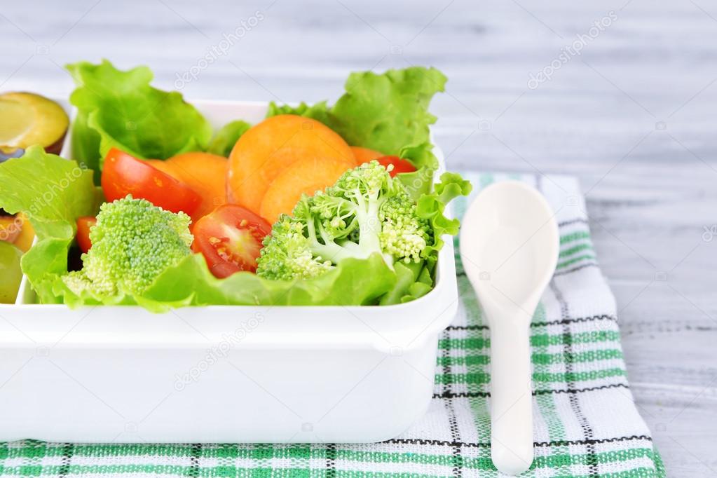 Tasty vegetarian food in plastic box on wooden table — Stock Photo © belchonock 53063847