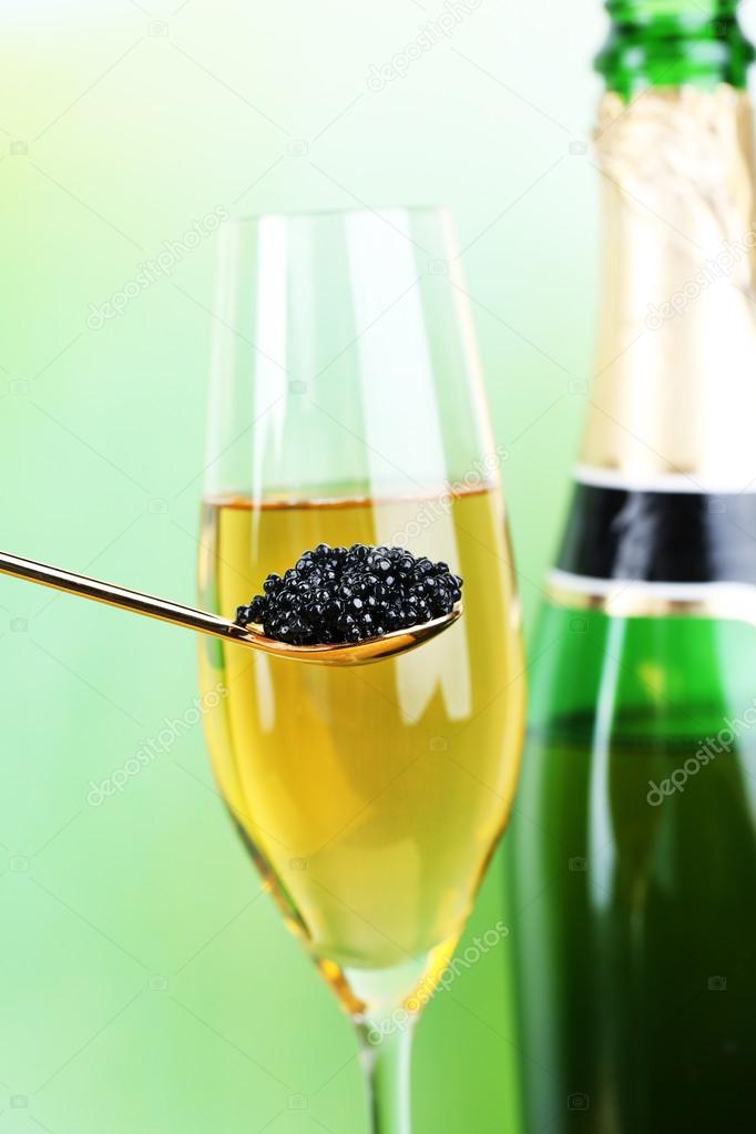 Goblet and bottle of champagne and spoon with black caviar
