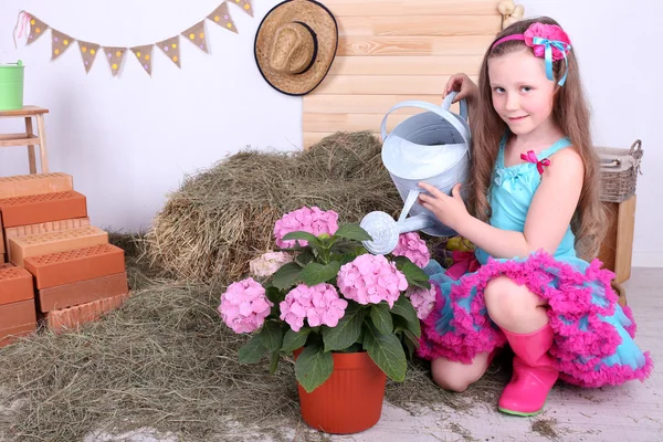 Hermosa niña pequeña en falda pequeña sosteniendo regadera sobre fondo de estilo país — Foto de Stock