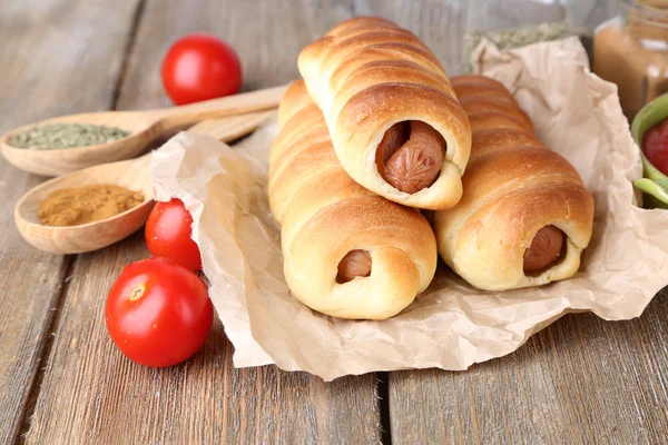 Baked sausage rolls on wooden table close-up — Stock Photo, Image