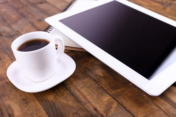 Tableta, taza de café y cuaderno sobre fondo de madera — Foto de Stock