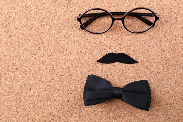 Glasses, mustache and bow tie forming man face on color background — Stock Photo, Image