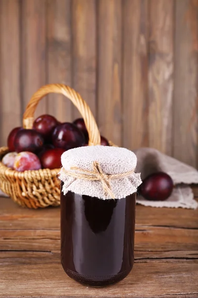 Tasty plum jam in jar and plums on wooden table close-up — Stock Photo, Image