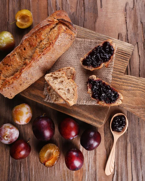 Chléb s povidly a švestky na dřevěný stůl detail — Stock fotografie