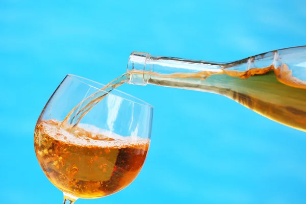 Vinho derramando em copo de vinho em fundo azul, close-up — Fotografia de Stock