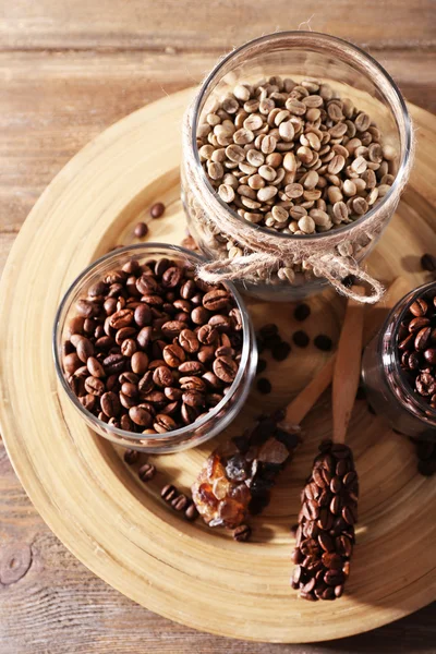 Coffee beans in jars on bamboo plate on wooden background — Stock Photo, Image