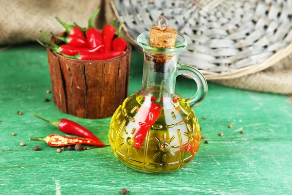 Aceite de oliva infundido natural casero con chiles rojos en botella sobre fondo de madera color — Foto de Stock