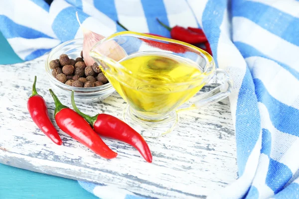 Conjunto de especias y aceite de oliva en salsa-barco de cristal, en la tabla de cortar, sobre fondo de madera color — Stockfoto