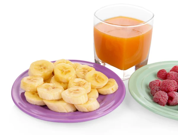 Slices of bananas with berries on plate with glass of juice isolated on white — Stock Photo, Image
