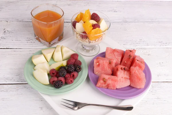 Slices of fruits with berries and muesli on wooden table — Stock Photo, Image