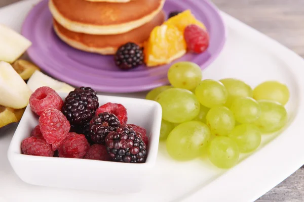 Pannenkoek met fruit en bessen op plaat op houten tafel — Stockfoto