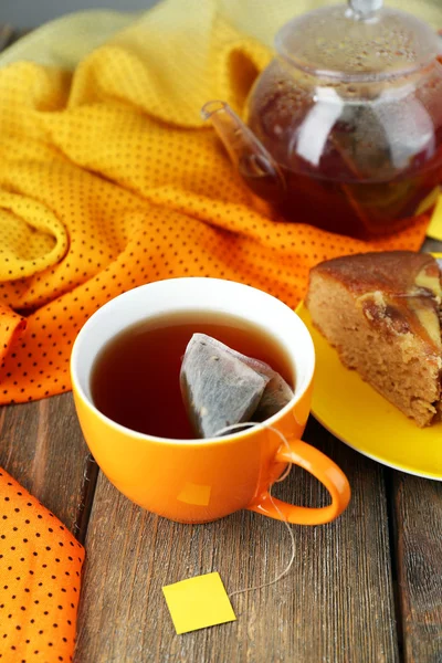 Taza de té, tetera y bolsitas de té en la mesa de madera de cerca —  Fotos de Stock