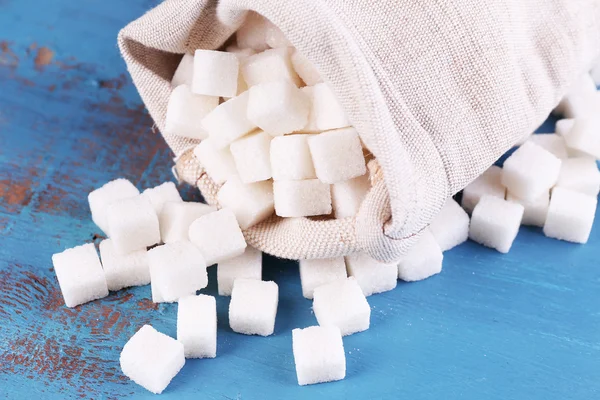 Ραφιναρισμένη ζάχαρη σε τσάντα σε χρώμα ξύλινα φόντο — Φωτογραφία Αρχείου