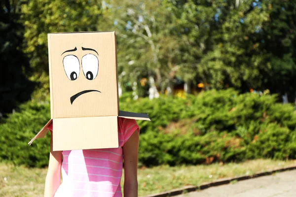 Vrouw met kartonnen doos op haar hoofd met droevig gezicht, buitenshuis — Stockfoto