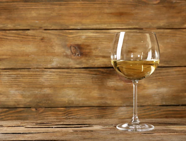 Kieliszek białego wina na drewnianym stole na tle ściany drewniane — Zdjęcie stockowe