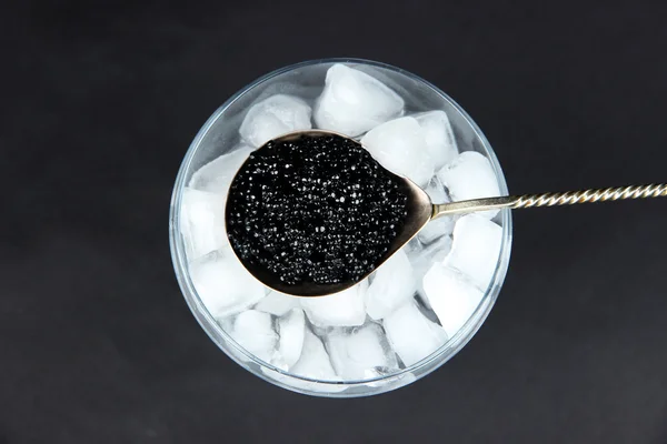 Caviar preto em colher de metal e gelo — Fotografia de Stock