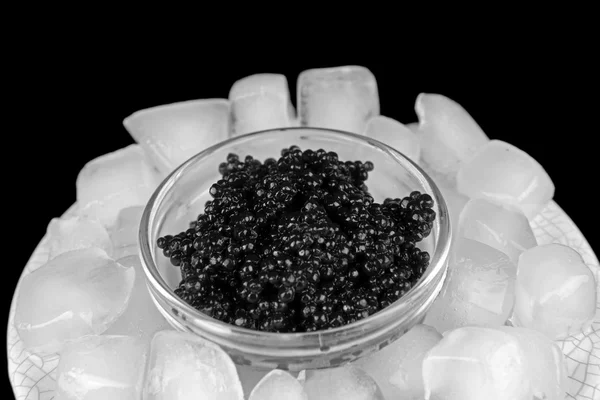 Caviale nero in ciotola di vetro e ghiaccio in piatto di plastica — Foto Stock