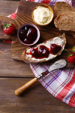 ahşap arka plan üzerinde ev yapımı tereyağı ve çilek reçel taze tost