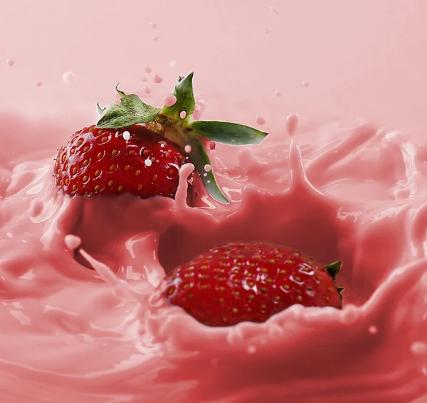 Köstliche frische Erdbeeren, die in spritzende Milch fallen — Stockfoto