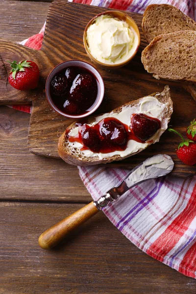 Verse toast met zelfgemaakte boter en strawberry jam op houten achtergrond — Stockfoto
