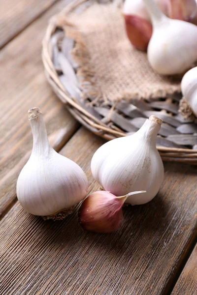 Verse knoflook op rieten mat, op houten achtergrond — Stockfoto